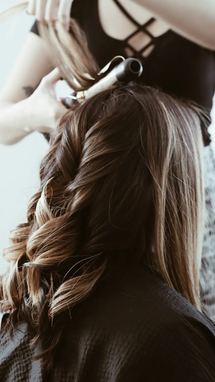 Cabeleireira modelando ondas com babyliss em cabelo castanho.