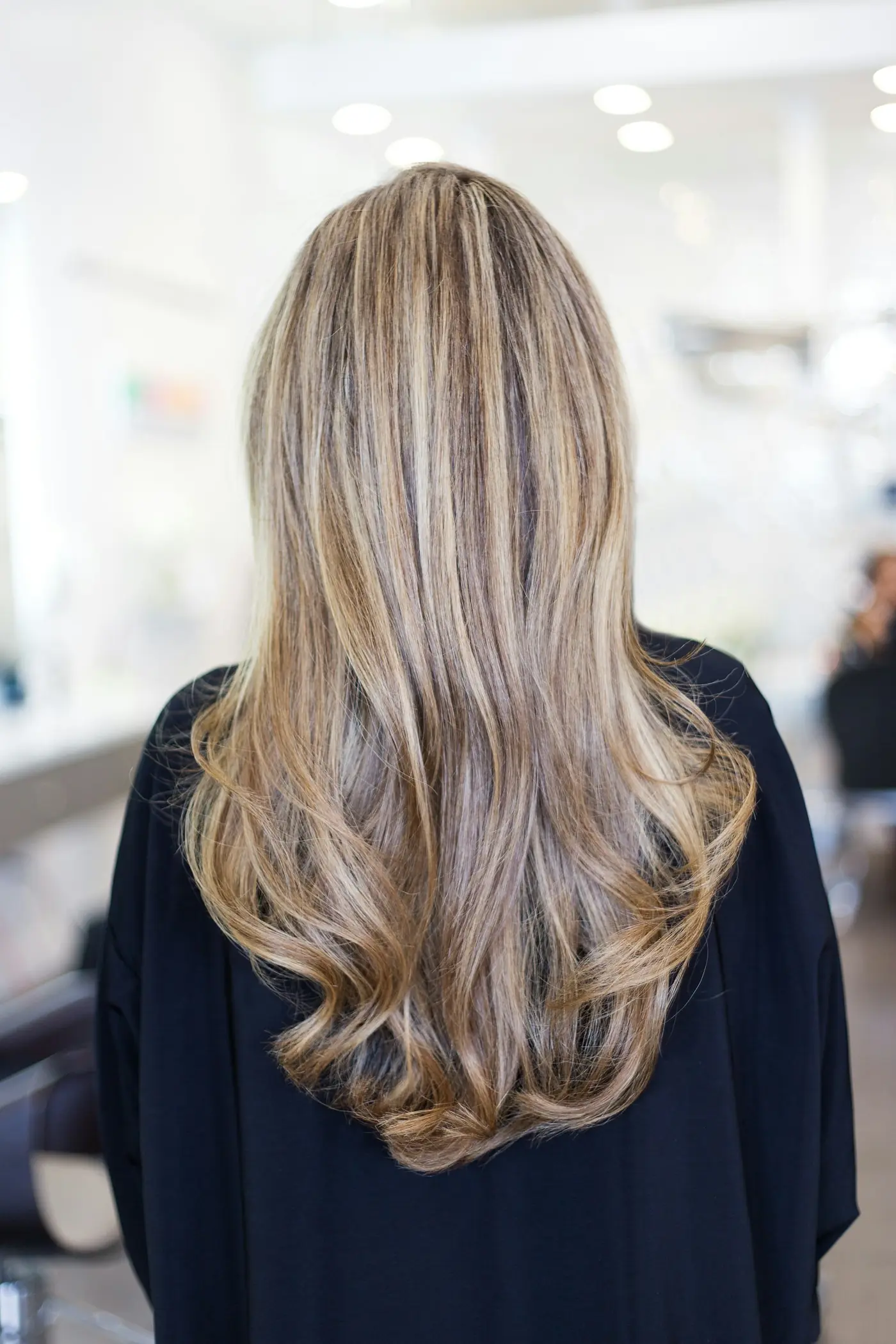 Cabelo longo com mechas loiras e castanhas, visto de costas.